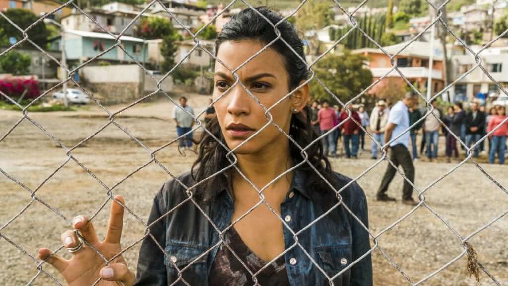 Fear the Walking Dead: “Los Muertos” Review Luciana in Fear the Walking Dead looking through a fence at the infected