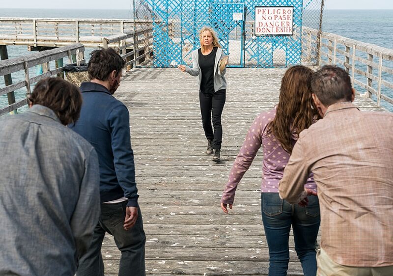 Madison leading a group of the infected down a pier