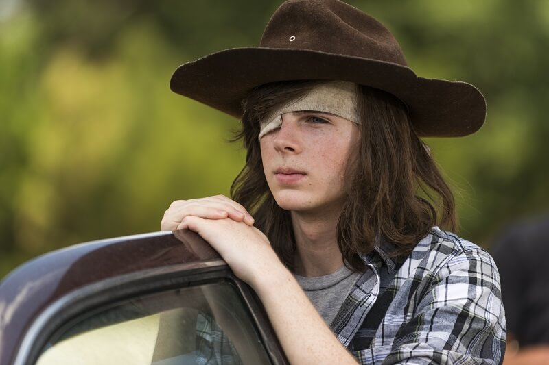 Carl leaning on a car door in The Walking Dead