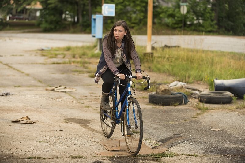 Enid riding a bike on the street in The Walking Dead