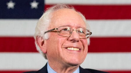 ‘The American political system is broken’: Vermont Residents Blast Billionaire Election Spending While Families Struggle A close-up of Bernie Standers, smiling in front of an American flag