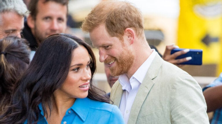 Prince Harry and Meghan Markle Fire ‘Critical’ Staff Members To Save Money: ‘Just Insane’ Prince Harry appears to whisper something to his wife, Meghan Markle.
