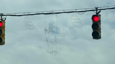 Wire art of a woman in a swing dangles from a streetlight in Baltimore Maryland