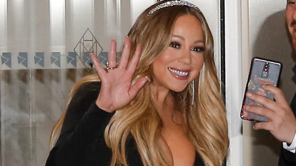 Mariah Carey waves to cameras as she exits her hotel.