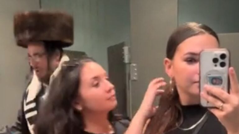 Women in a restroom, plus a man dressed in Orthodox Jewish clothing