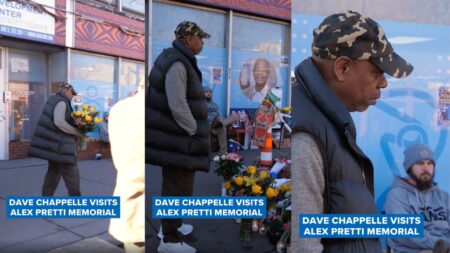 Dave Chappelle standing silently at a flower-covered memorial site in Minneapolis, Minnesota, after placing a bouquet among tributes for Alexi Pretti.