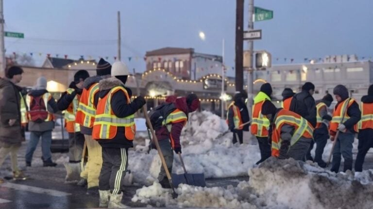 Group of city workers clearing a pile of snow on a New York street after a blizzard.