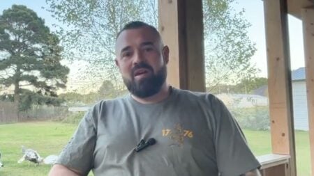 Arkansas dad Aaron Spencer speaking on a porch in a grey t-shirt during an interview after winning the Lonoke County Republican primary for sheriff.