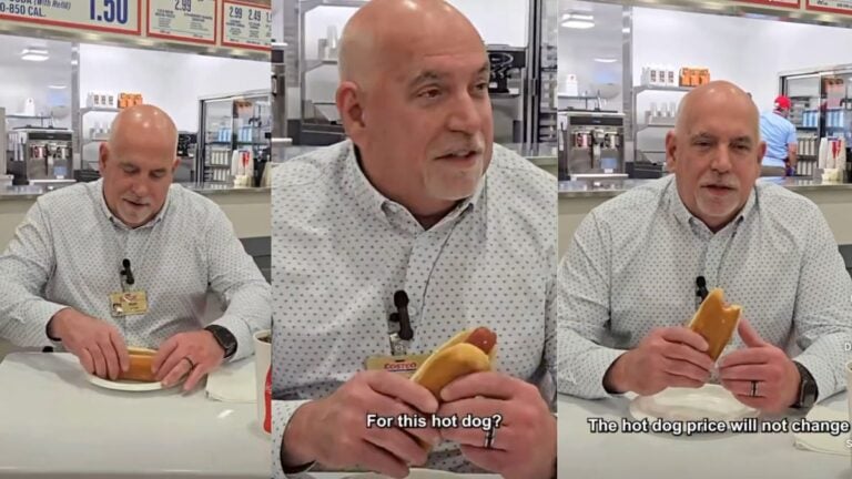 Washington's Costco CEO Ron Vachris sitting at a food court table taking a confident bite of the iconic $1.50 hot dog and soda combo in a viral Instagram video.