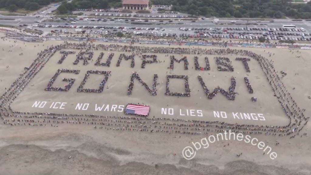 Aerial drone footage of hundreds of protesters forming a 600-foot human banner spelling Trump Must Go Now on San Francisco Ocean Beach California during No Kings Day on March 28 2026