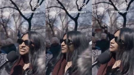 A young woman at an outdoor protest rally speaks seriously to an off-camera interviewer while holding a sign, unaware she is responding earnestly to a pun-based trick question about the Strait of Hormuz.