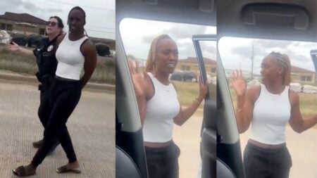 A Black woman identified as Kathleen Booker holds her hands raised during a traffic stop on a Texas road, speaking to officers outside her vehicle while a toddler sits in a car seat in the back, as police point out their vehicle match claim during a high-risk stop.