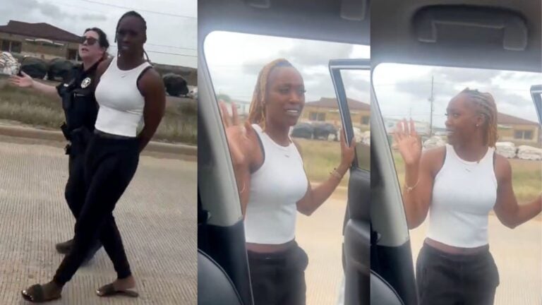 A Black woman identified as Kathleen Booker holds her hands raised during a traffic stop on a Texas road, speaking to officers outside her vehicle while a toddler sits in a car seat in the back, as police point out their vehicle match claim during a high-risk stop.