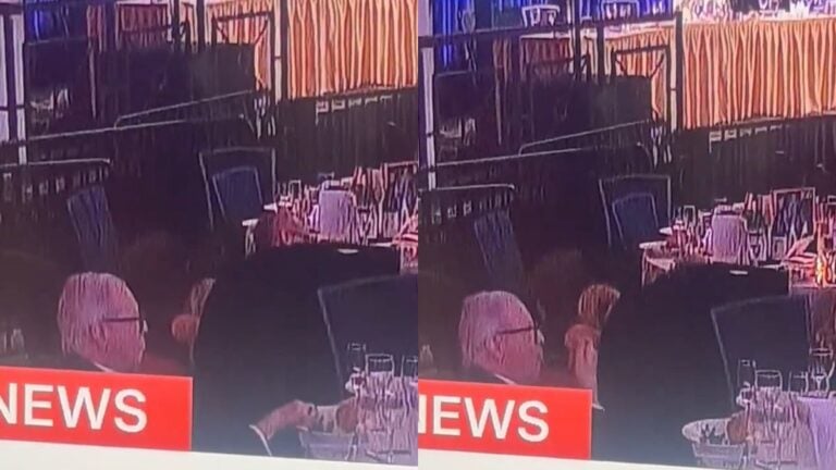 An elderly man with white hair and glasses sits calmly at his table inside the Washington Hilton ballroom during the White House Correspondents' Dinner, fork in hand, continuing to eat as staff and guests scramble around him during a security incident.