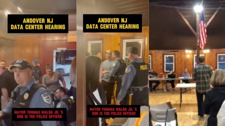 A man in a plaid shirt stands and addresses Andover Township Committee officials inside the Hillside Barn in Newton, New Jersey, gesturing emphatically as a packed crowd of residents looks on during a heated May 7, 2026 public meeting over a proposed AI data center, moments before a community member is arrested.