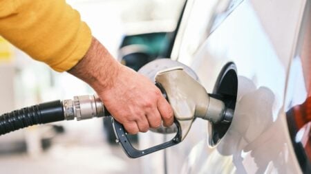 Close-up of a person refueling a car with a gas nozzle at a station.