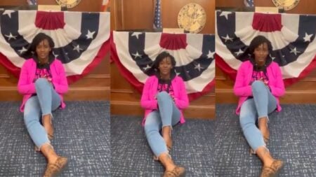 Florida State Representative Angie Nixon sits cross-legged on the floor of Governor Ron DeSantis' Capitol office lobby in Tallahassee, wearing her signature pink jacket, during a five-hour sit-in protest against newly passed congressional redistricting maps on May 15, 2026.
