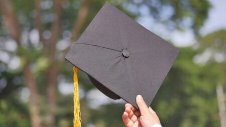 Texas School Under Fire After 6-Year-Old With Developmental Delay Is Allegedly Made to Watch Graduation Through Locked Doors: ‘This Is Heartbreaking’ A hand holding a graduation cap, symbolizing achievement and celebration.