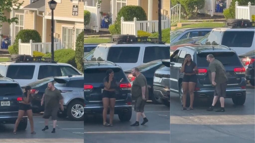 New Jersey Man Aggressively Confronts Woman In A Parking Lot While She Pleads For Help: ‘We Need More Insane Asylums To House These Lunatics’ A still from a viral video showing a man in a dark olive t-shirt and shorts aggressively approaching a woman standing near a dark Jeep in a residential parking lot in Mt. Laurel, New Jersey, while she holds a phone to her ear.