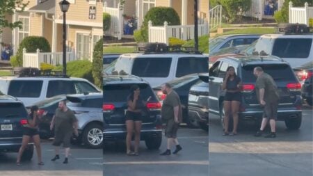 New Jersey Man Aggressively Confronts Woman In A Parking Lot While She Pleads For Help: ‘We Need More Insane Asylums To House These Lunatics’ A still from a viral video showing a man in a dark olive t-shirt and shorts aggressively approaching a woman standing near a dark Jeep in a residential parking lot in Mt. Laurel, New Jersey, while she holds a phone to her ear.
