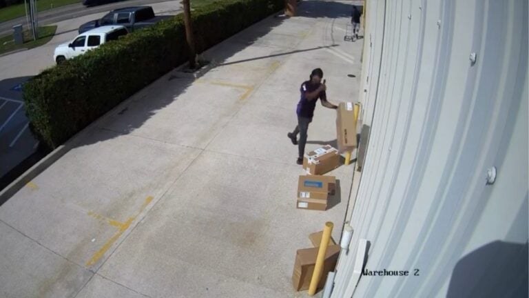 Security camera footage from a Texas warehouse loading dock shows a FedEx worker in a dark shirt repeatedly dropping, slamming, and kicking boxes containing approximately $20,000 worth of Lutron equipment on May 26, 2026, while a second worker handles deliveries nearby.