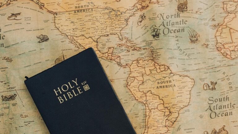 Texas Outraged as Bible Reading Could be Enforced in Schools: ‘The Only Sharia Law Rapidly Appearing is a Christian Version’ A bible on top of a mapa showing North America.