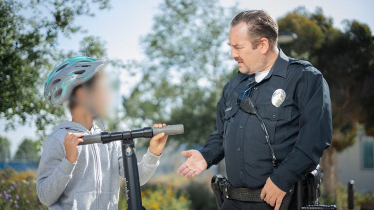 Angry Indiana Mother Says She ‘Lives in MAGA Hell’ After Neighbors Allegedly Report Her Children to Police for Walking Outside Alone Police officer speaking to a boy