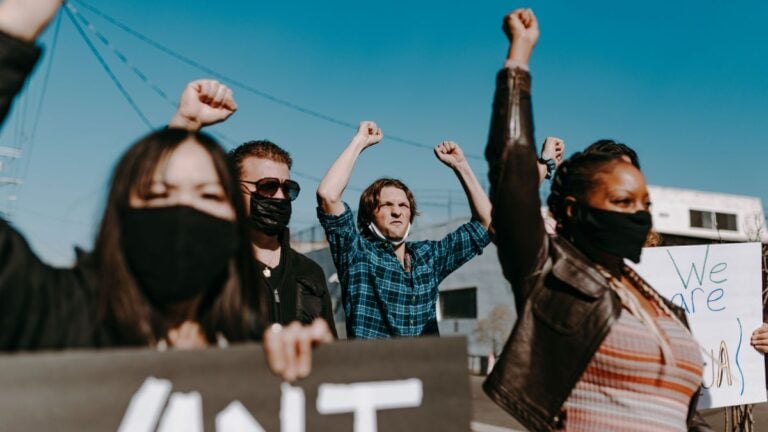 Florida ‘Teen Takeover’ At Clearwater Beach Turns Violent, 17-Year-Old Shot: ‘The Parents Have To Do Better’ A diverse group of activists protesting peacefully outdoors, showing unity and solidarity.