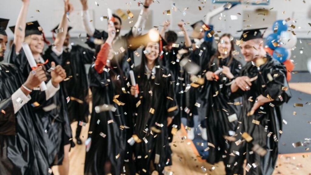 Awkward Illinois Graduation Moment Leaves Viewers Divided: ‘The Confidence, the Timing, the Reaction…’ Excited graduates toss confetti in celebration, marking a special achievement moment indoors.
