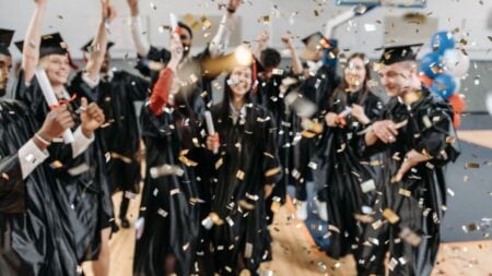 Awkward Illinois Graduation Moment Leaves Viewers Divided: ‘The Confidence, the Timing, the Reaction…’ Excited graduates toss confetti in celebration, marking a special achievement moment indoors.