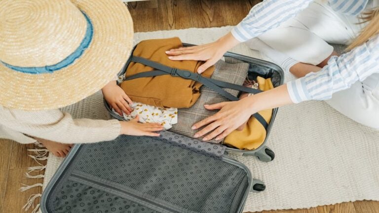 Parent and child pack clothing into a suitcase before a family vacation