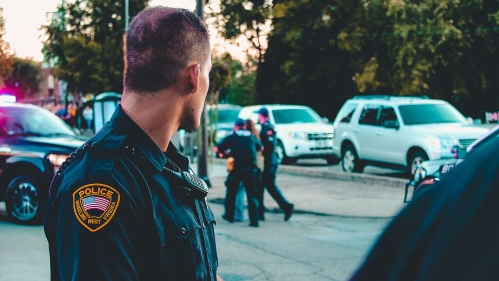 Police officer monitoring a street scene with patrol vehicles in Wheeling, WV.