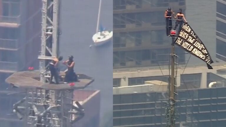 Two masked climbers stand atop the Empire State Building spire after unfurling a peace banner in New York City.