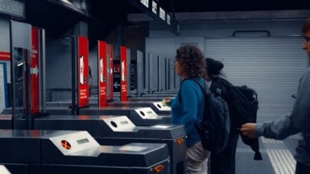 Georgia Woman Destroys MARTA’s New $130 Million Glass Fare Gate To Avoid Paying: ‘Physical Security Is Still Essential’ Urban commuters using turnstiles at a modern subway station, showcasing daily public transportation routine.