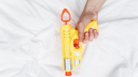 Bright yellow and orange water gun held by an adult hand.