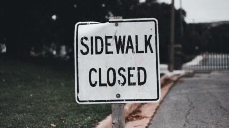 California Man Gets Angry at Workers After Sidewalk Is Blocked Off for Construction: ‘Just Go About Your Business, Jeez’ Close-up of a 'Sidewalk Closed' sign on a street, indicating obstruction.