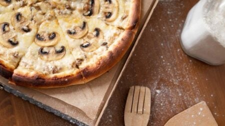 New Yorker Walks Into Pizza Shop And Finds Worker’s Bare Foot On Dough Mixer: ‘He Was Just Trimming His Toenails’ Delicious mushroom pizza with cheese in a cardboard box on a wooden table with flour.