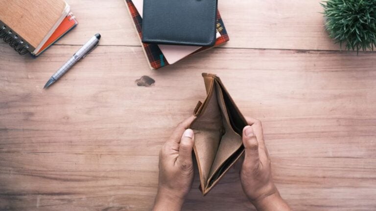 California Loses 10,000 Jobs After Officials Skip Meetings With $3.2 Billion Port Company: ‘Now We Have Neither Houses Nor Jobs’ Top view of hands holding an open empty wallet on a wooden desk with notebooks and pen.