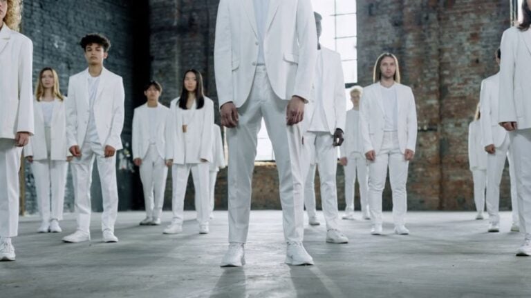 Diverse group of individuals wearing white suits in an urban, industrial environment.