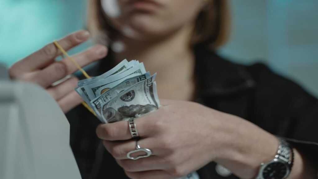 Close-up of a person counting dollar bills indoors.