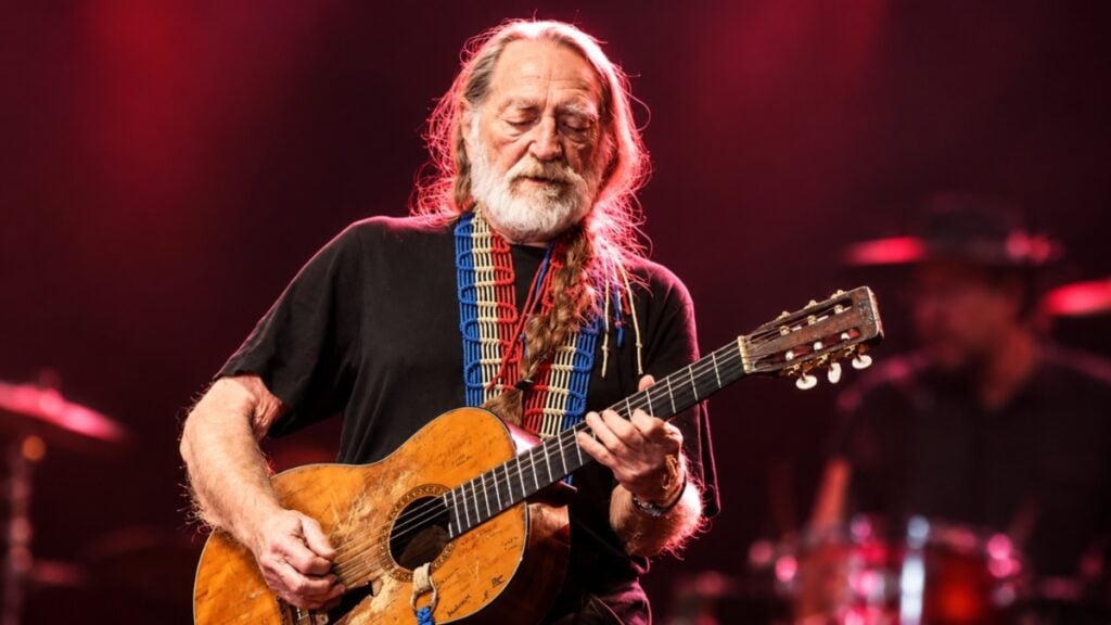 Texas Legend Willie Nelson Declares War at 93 to Save the Tiny Hometown Where He Can Still See the Stars: ‘Invading Our Land’ Willie Nelson playing guitar on stage