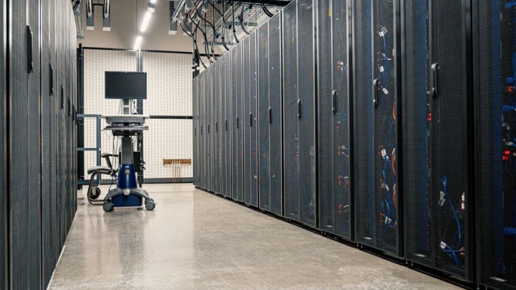 New Mexico Woman Knocked to the Ground and Arrested at Data Center Protest Meeting: ‘They Are All Getting Paid Behind Closed Doors’ Modern data center corridor with server racks and computer equipment. Ideal for technology and IT concepts.
