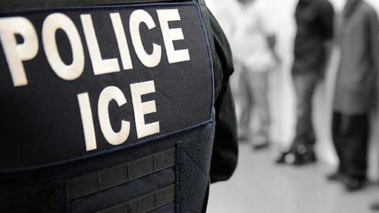 An ICE officer oversees an immigration enforcement operation.