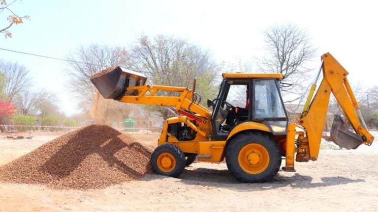 California Woman Refuses To Move Away From Excavator, Falls Into Bucket And Gets Stuck: ‘Play Stupid Games, Win Stupid Prizes’ A yellow excavator moving gravel at an outdoor construction site during the day with clear skies.