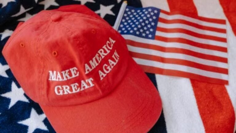 Red cap with 'Make America Great Again' text on US flag background.
