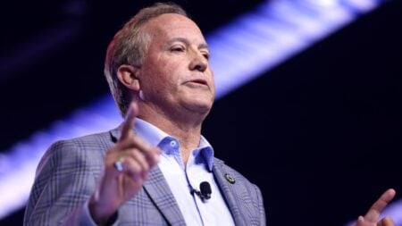 A man got escorted out of a Texas rally after shouting an accusation at Ken Paxton. The video is drawing strong online reactions.