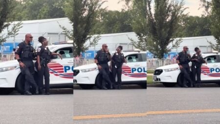 Two uniformed DC police officers stand beside a police vehicle.