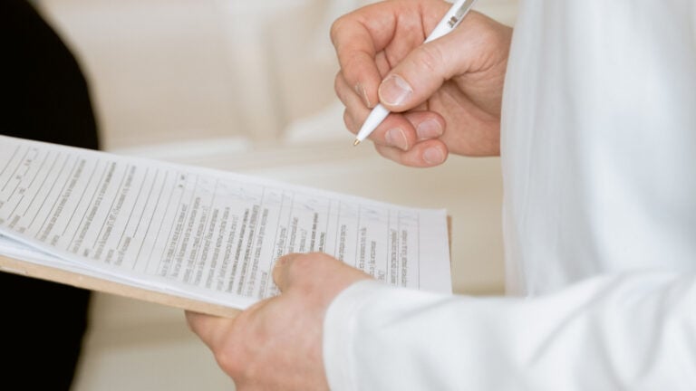 Talk About Another Health Problem, and You Could Get Charged for It A medical professional in a white coat examines a clipboard with patient documents