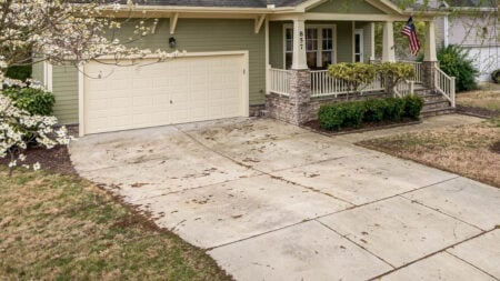 An American suburban home with a lush front yard, driveway, and trees