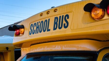 Yellow school bus close-up showing front lights and signage.
